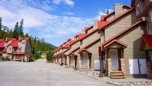 Un hilera de edificios al estilo de cabañas de troncos, con techos rojos, pilares de piedra y un cielo despejado.