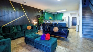Ein modernes Wohnzimmer mit einem Ecksofa, einem Hocker und einem Essbereich mit Bar.