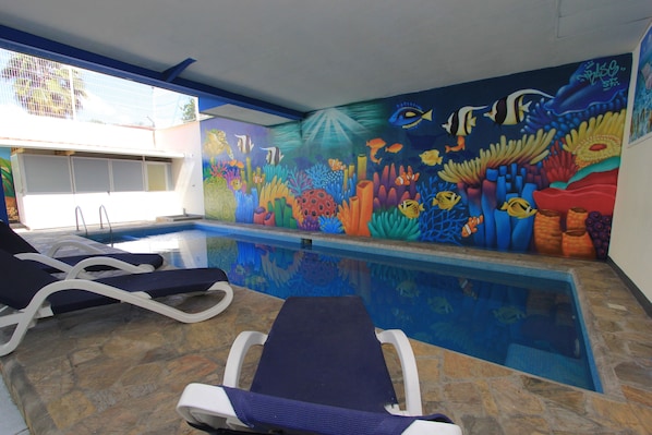 A swimming pool with lounge chairs and a mural of marine life.