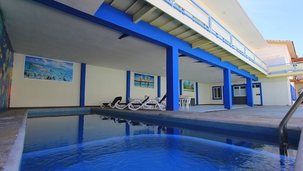 A swimming pool with lounge chairs and a covered area with artwork. - Hotel Xestalito (Santa María Huatulco)