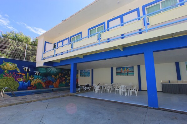 Un bâtiment à la façade bleue et blanche, doté d’un balcon avec des balustrades et orné d’une fresque représentant la vie marine.