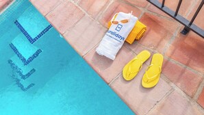 Et poolområde med fliser, et håndklæde og flip-flops.