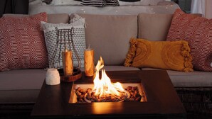 Ein gemütlicher Außenbereich mit Feuerstelle, Lichterketten und einem überdachten Bereich mit Whirlpool.