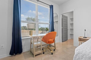 A bedroom with a bed, a desk with a chair, a lamp, and a wardrobe. - Ideal for long-term stays-available for 14 days and Beyond. (Temple)