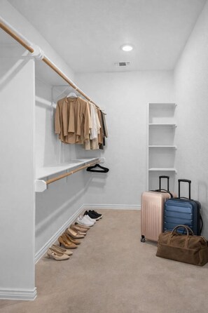 A walk-in closet with hanging space and shelves, a pair of suitcases, and a duffel bag. - Ideal for long-term stays-available for 14 days and Beyond. (Temple)