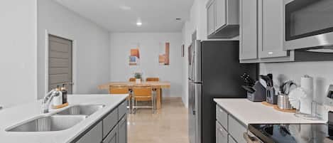 A modern kitchen with grey cabinets, stainless steel appliances, and a central island with a sink.