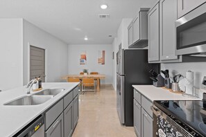 Una cocina moderna con gabinetes grises, electrodomésticos de acero inoxidable y una isla central con pileta.