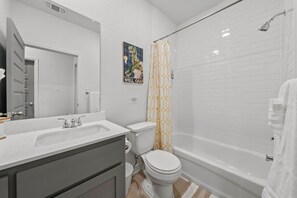 A bathroom with a white sink, toilet, and bathtub. There is a shower curtain with a geometric pattern. - Ideal for long-term stays-available for 14 days and Beyond. (Temple)