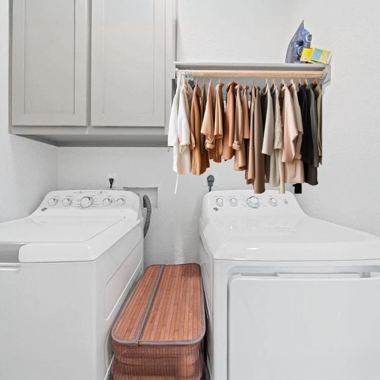 Une buanderie équipée de deux machines à laver, d’un étendoir à linge et d’un panier à linge en bois.