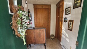 Un pasillo con una puerta de madera, una pequeña mesa con un florero y un cuadro decorado con fotografías.