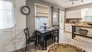A dining area with a black table, four chairs, a clock, and a window with blinds. - Hot Tub - Fire Pit - Single Level Ranch (Matthews)