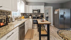 A modern kitchen with white cabinets, a stainless steel refrigerator, a microwave, and a stove. - Hot Tub - Fire Pit - Single Level Ranch (Matthews)