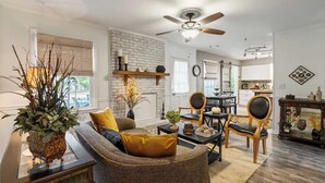 A living room with a sofa, coffee table, and chairs, a fireplace, and a dining area with a table and chairs. - Hot Tub - Fire Pit - Single Level Ranch (Matthews)