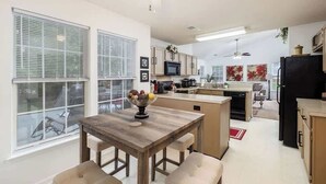 Una cocina moderna con zona de comedor, ventanas grandes y ventilador de techo.