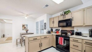 Una cocina moderna con armarios color beige, una estufa negra y un microondas.