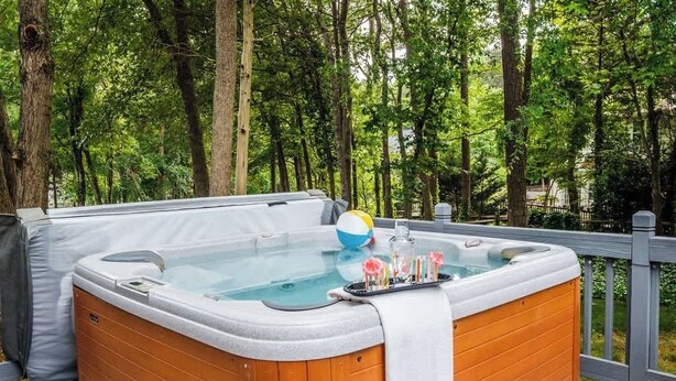 Un jacuzzi en una terraza de madera rodeado de árboles.