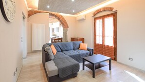 A cozy living room with a sectional sofa, a small table, and a kitchen area in the background.