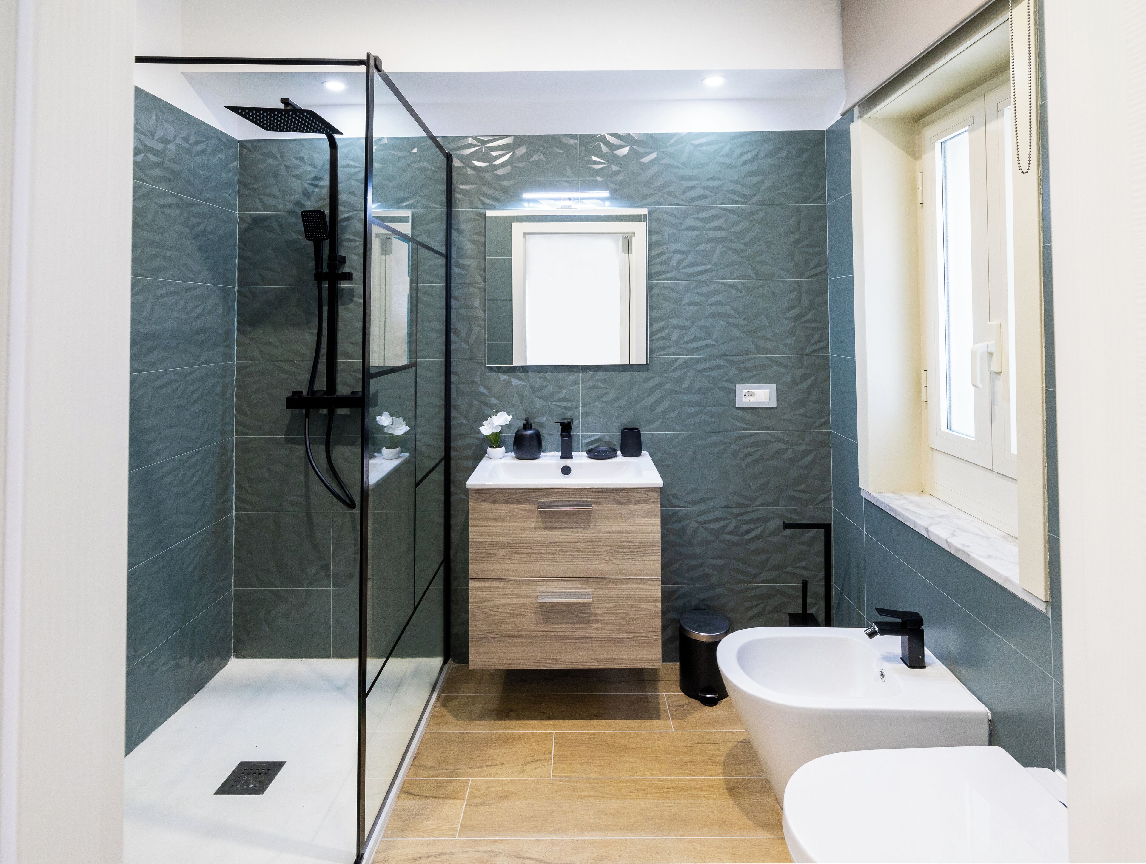 A modern bathroom with a glass-enclosed shower, a freestanding bathtub, and a vanity with a mirror.