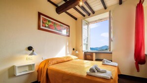 A bedroom with a bed, a window, a painting, and a red curtain. - Stunning apartment in Recco with kitchen (Recco)