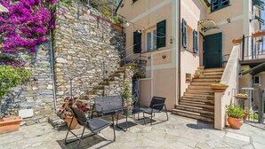 A stone staircase leading to a building with a balcony, outdoor seating with chairs and a table, and potted plants. - Stunning apartment in Recco with kitchen (Recco)