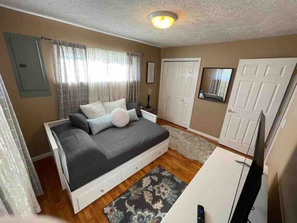 Un dormitorio con cama, cómoda, espejo y puerta.