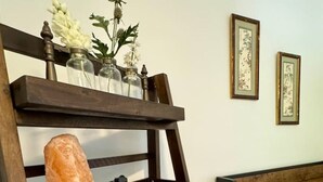 Una cama con cabecera de madera, una mesita de noche con una lámpara de sal, una planta pequeña en maceta y un control remoto.