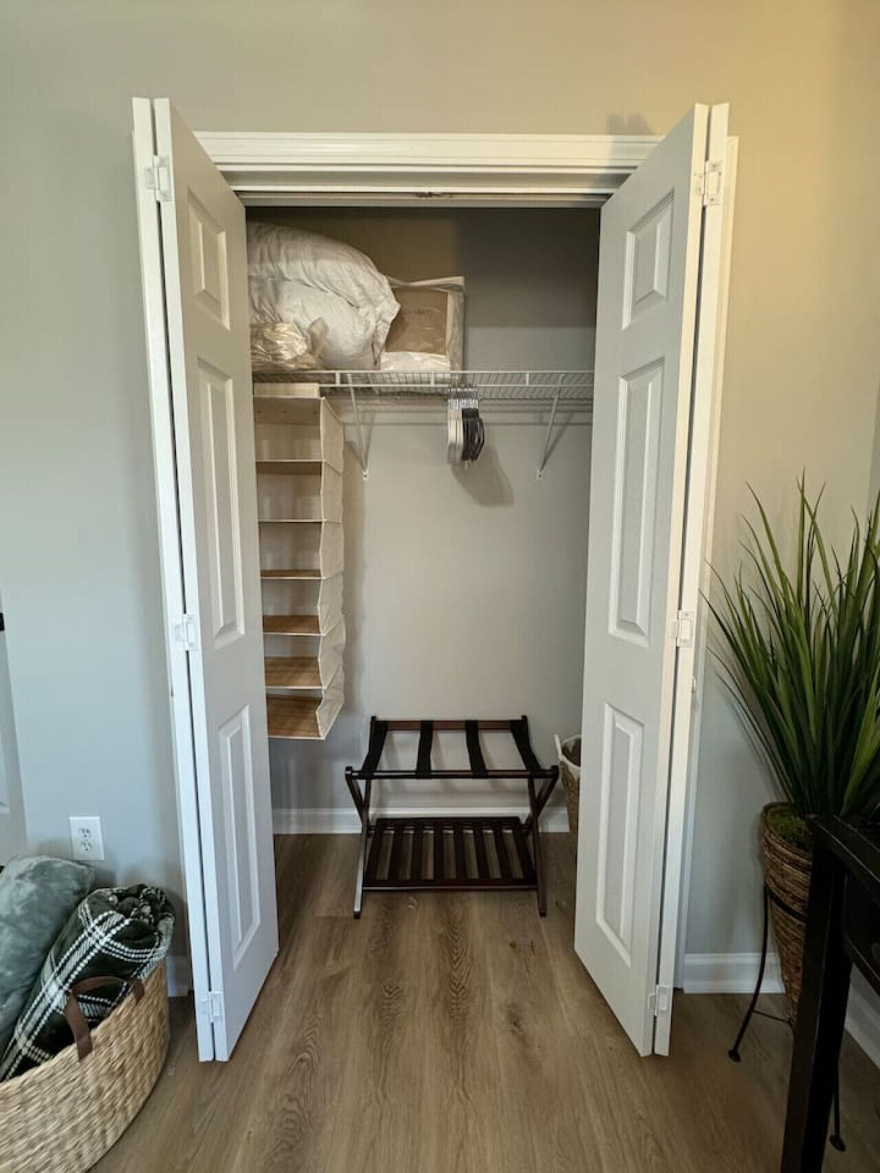 A walk-in closet with open doors, shelves, and a bench.