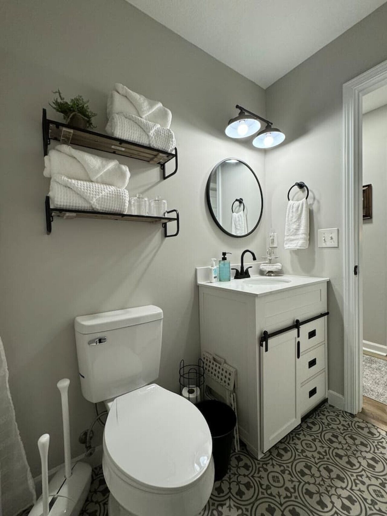 A bathroom with a toilet, sink, and towel rack. There are two towel racks with towels and a small plant.
