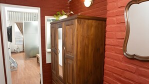A wooden wardrobe in a room with a red brick wall and a white door. - Home in downtown-Maipu St. (Buenos Aires)