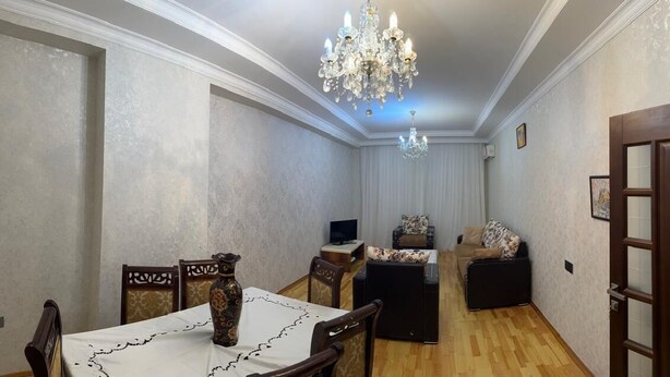 A dining area with a table, chairs, a chandelier, and a television. - Nermanov Home (Baku)