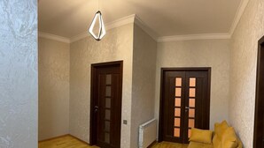 A room with wooden flooring, two doors, a radiator, and a yellow sofa. - Nermanov Home (Baku)