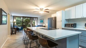 A modern kitchen with a large island, bar stools, and a ceiling fan.