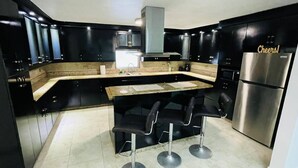 Una cocina moderna con gabinetes negros, un refrigerador de acero inoxidable y una zona de bar con taburetes.