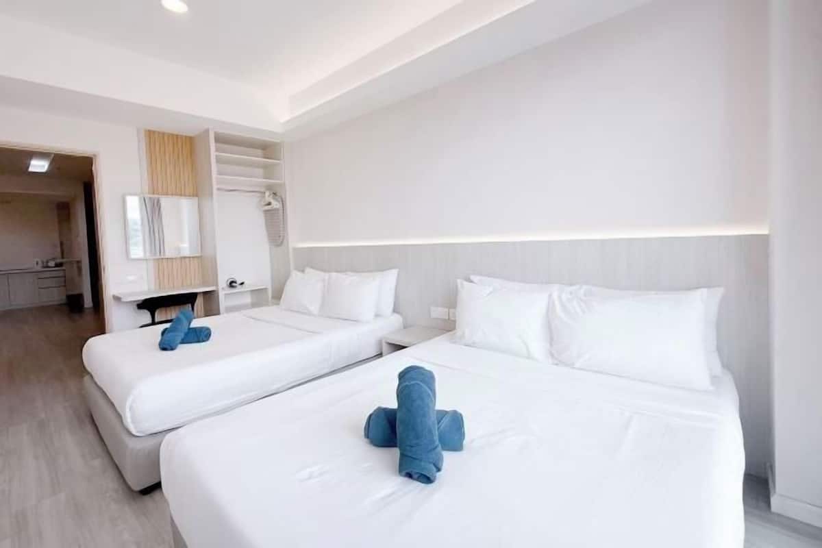 Une chambre d’hôtel avec deux lits, une armoire, un miroir et un petit coin salon.