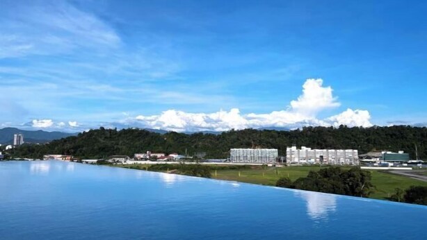 A large swimming pool with a view of a hotel and mountains in the background.