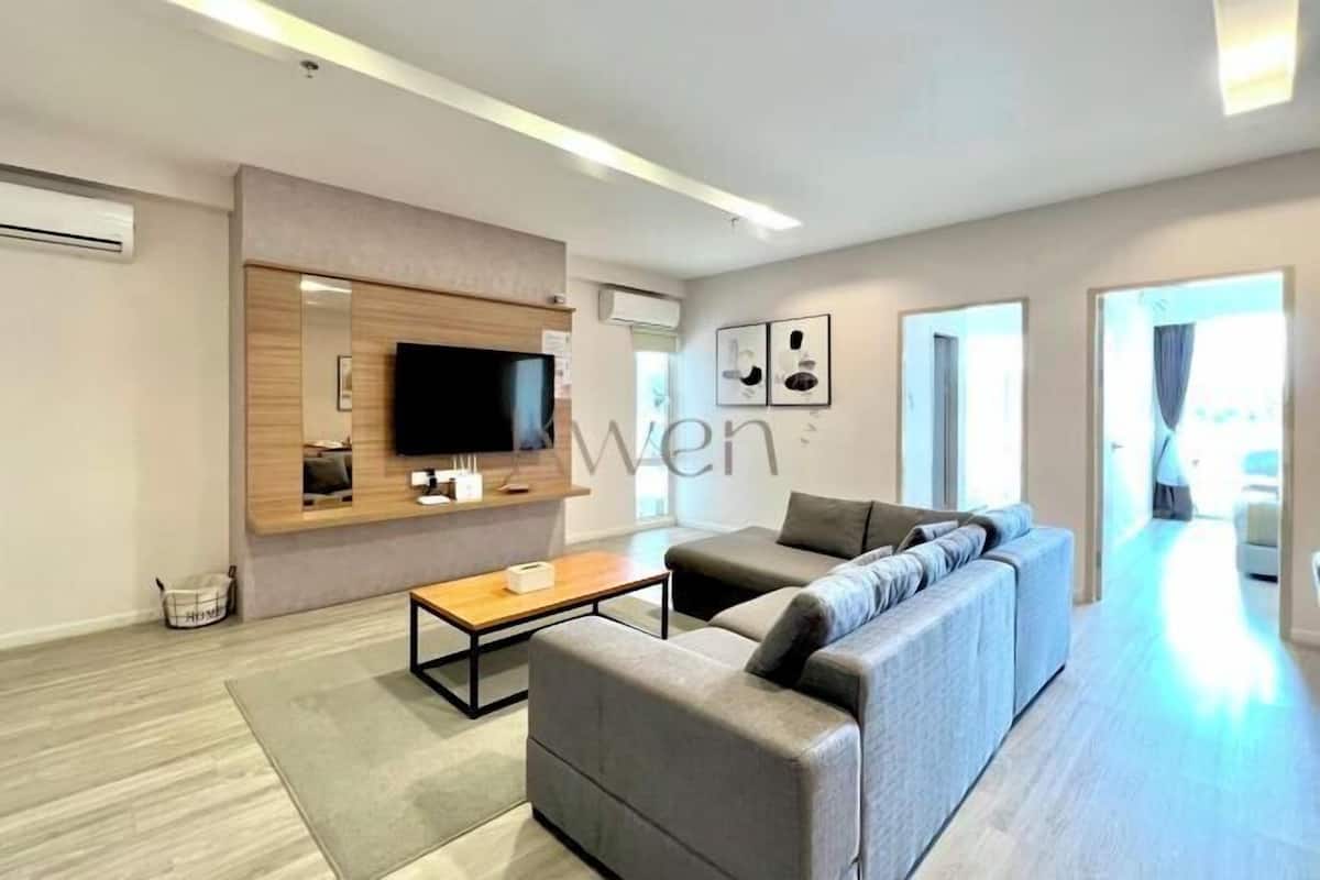 Un salon moderne avec un canapé, une table basse, un téléviseur à écran plat et un mur décoratif en bois.