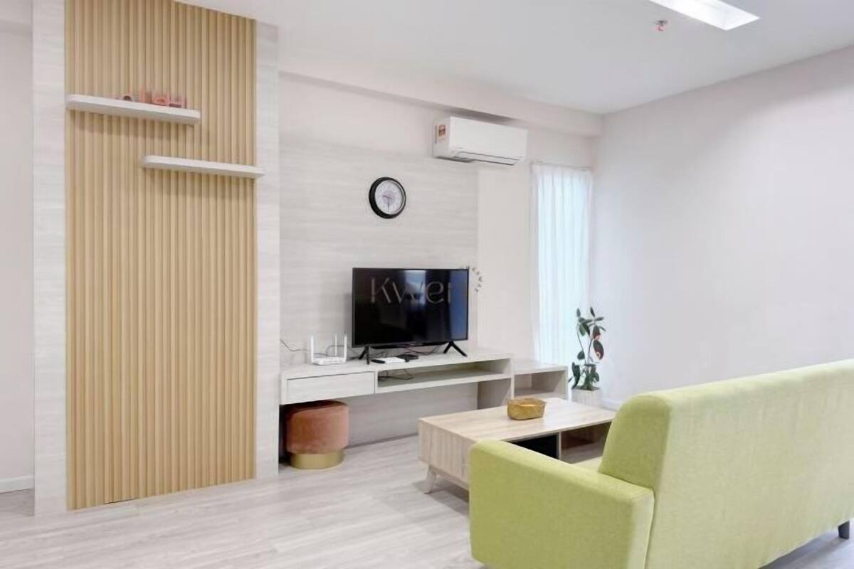 Un salon moderne équipé d’un téléviseur à écran plat, d’un canapé, d’une table basse et d’un climatiseur fixé au mur.