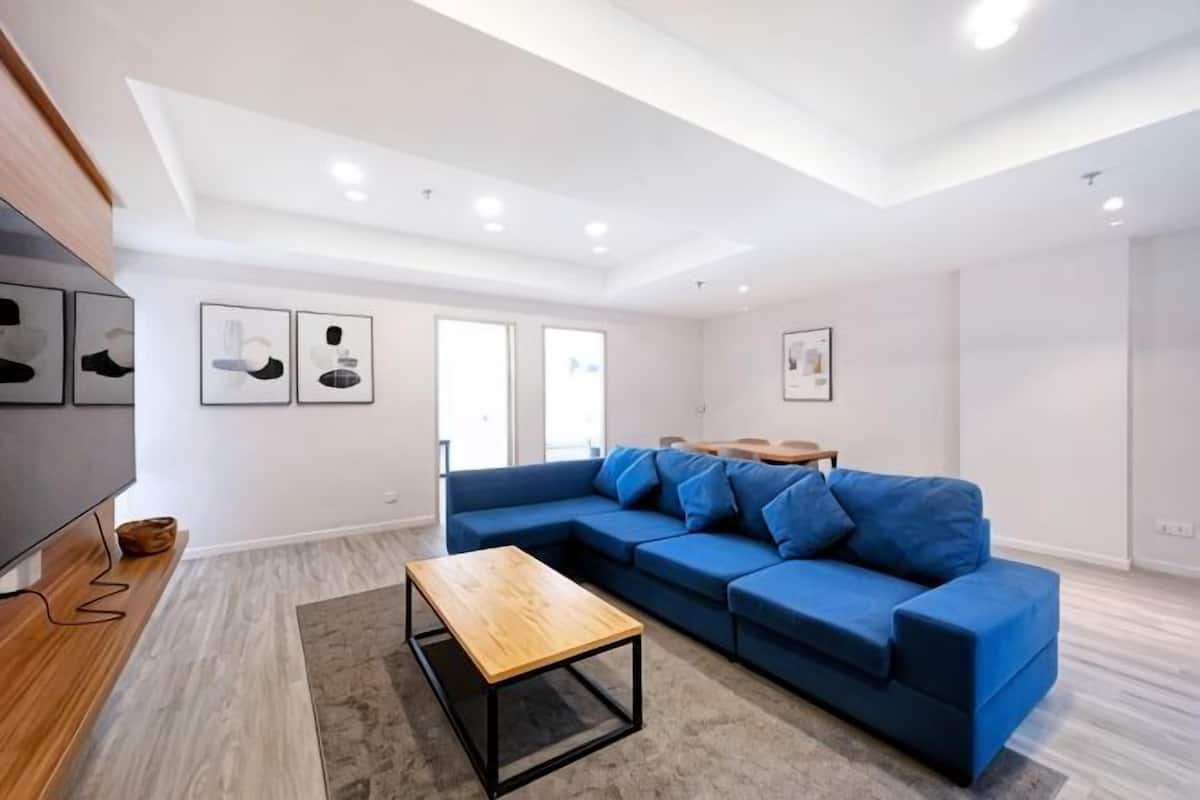 Un salon moderne avec un canapé d’angle, une table basse en bois et un téléviseur à écran plat.