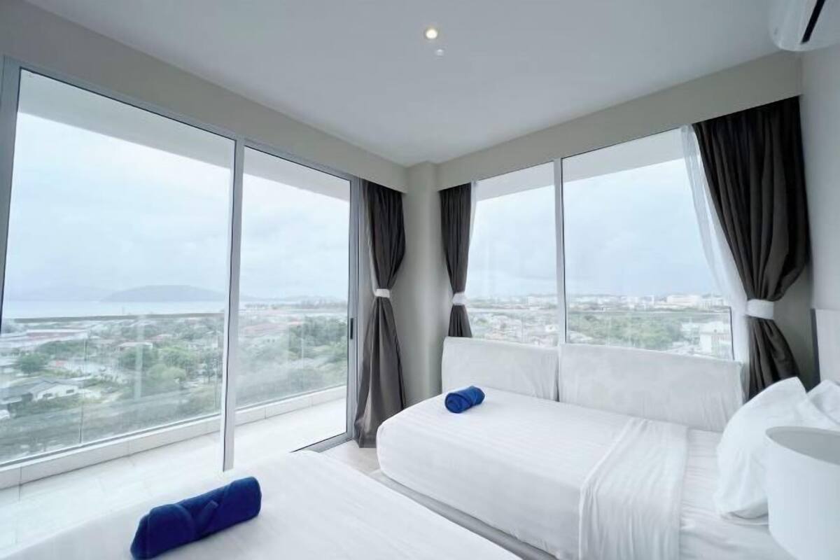 Une chambre d’hôtel avec deux lits, de grandes fenêtres et une vue sur le paysage urbain.