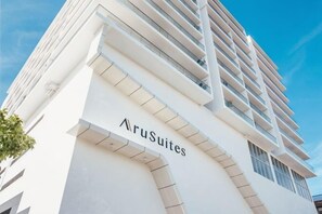 Un immeuble moderne et imposant, dont la façade porte l’inscription « AruSuites ».