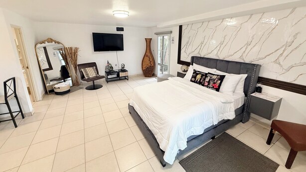 A modern hotel room with a large bed, a flat-screen TV, a vanity with a mirror, and a large vase. - Carolina Green House (Carolina)
