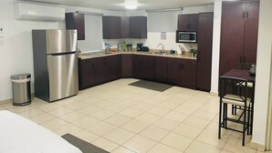 A compact kitchen with dark cabinets, a stainless steel refrigerator, a microwave, and a sink. - Carolina Green House (Carolina)