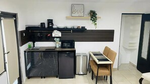 Compact kitchen with modern appliances, microwave, refrigerator, coffee maker, and sink, perfect for dining or working.