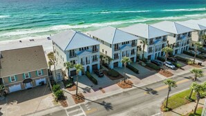A coastal hotel with multiple-story buildings, a beach view, and a parking area. - Coastal Breeze - Private Beach & Pool + Free Golf Cart (Miramar Beach)