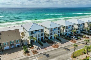 A coastal hotel with multiple-story buildings, a beach view, and a parking area.
