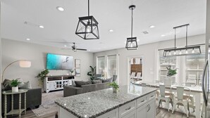 A modern kitchen with granite countertops, white cabinetry, and pendant lighting. - Coastal Breeze - Private Beach & Pool + Free Golf Cart (Miramar Beach)