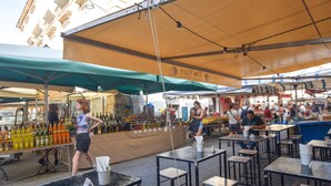 An outdoor market with tables and chairs under canopies, various food stalls, and a building in the background. - 1 bedroom nice home in Siracusa (Siracusa)