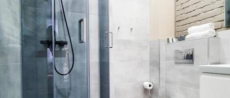 A modern bathroom with a glass-enclosed shower, a toilet, and a vanity with a mirror.