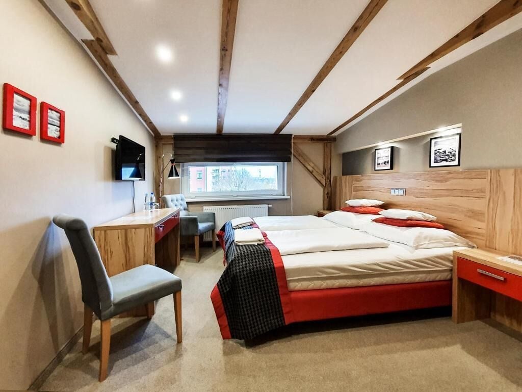 Un dormitorio con cama, escritorio, silla y ventana.