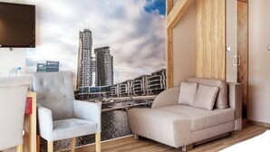 Une chambre d’hôtel moderne avec vue sur la ville, comprenant un canapé, un fauteuil et une armoire.